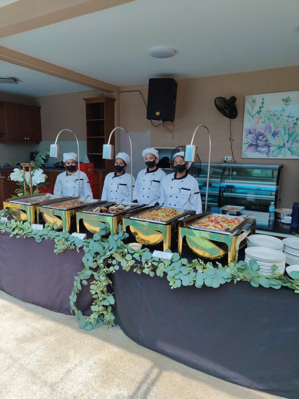 The real DLT Catering Services kitchen team behind a five-pan buffet spread