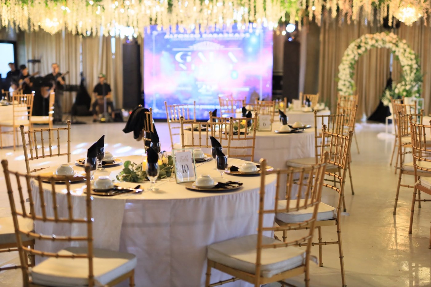 An elegant black-tie gala reception with a white floral arch