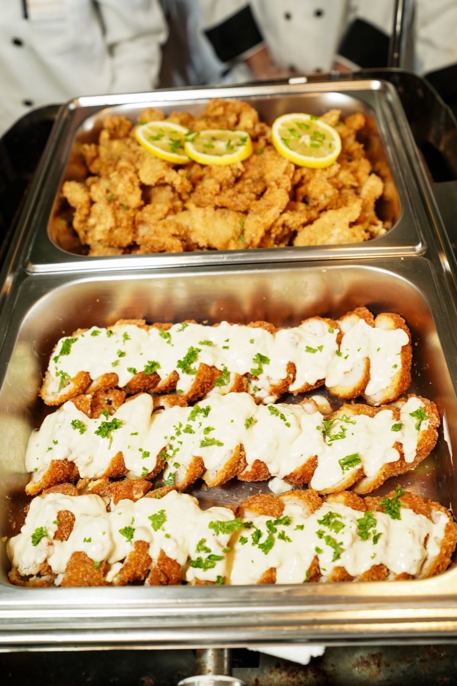 Fried chicken fillet with creamy sauce in a catering tray