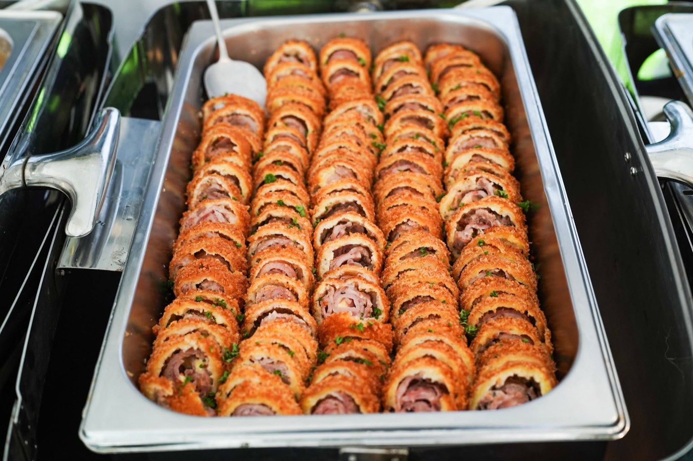 Sliced ham and cheese roulade in a catering tray