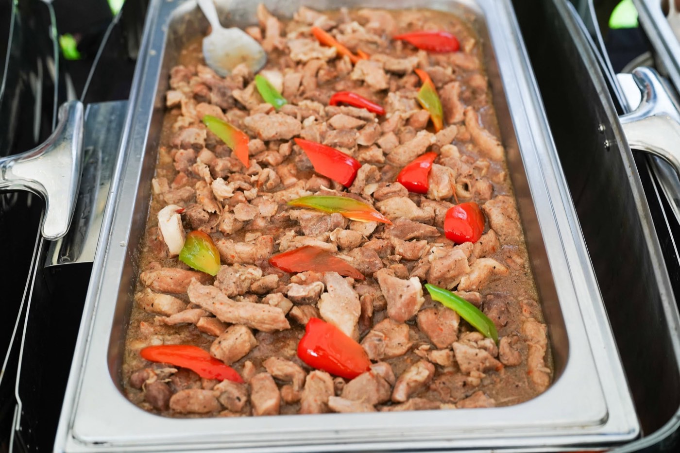 Pork in bell pepper sauce in a catering tray
