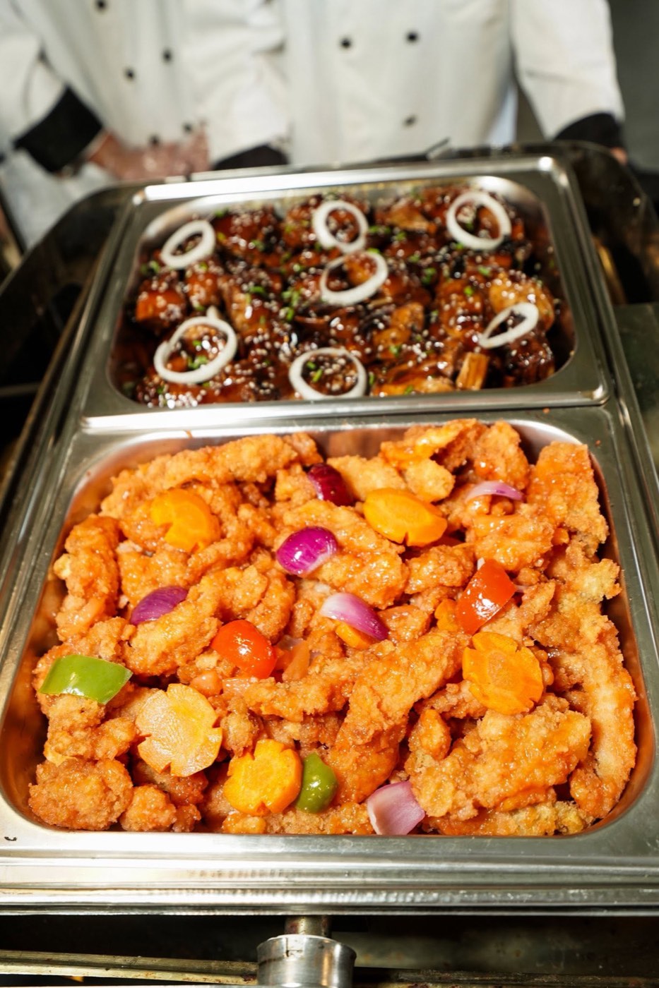 Sweet and sour glazed chicken in a catering tray